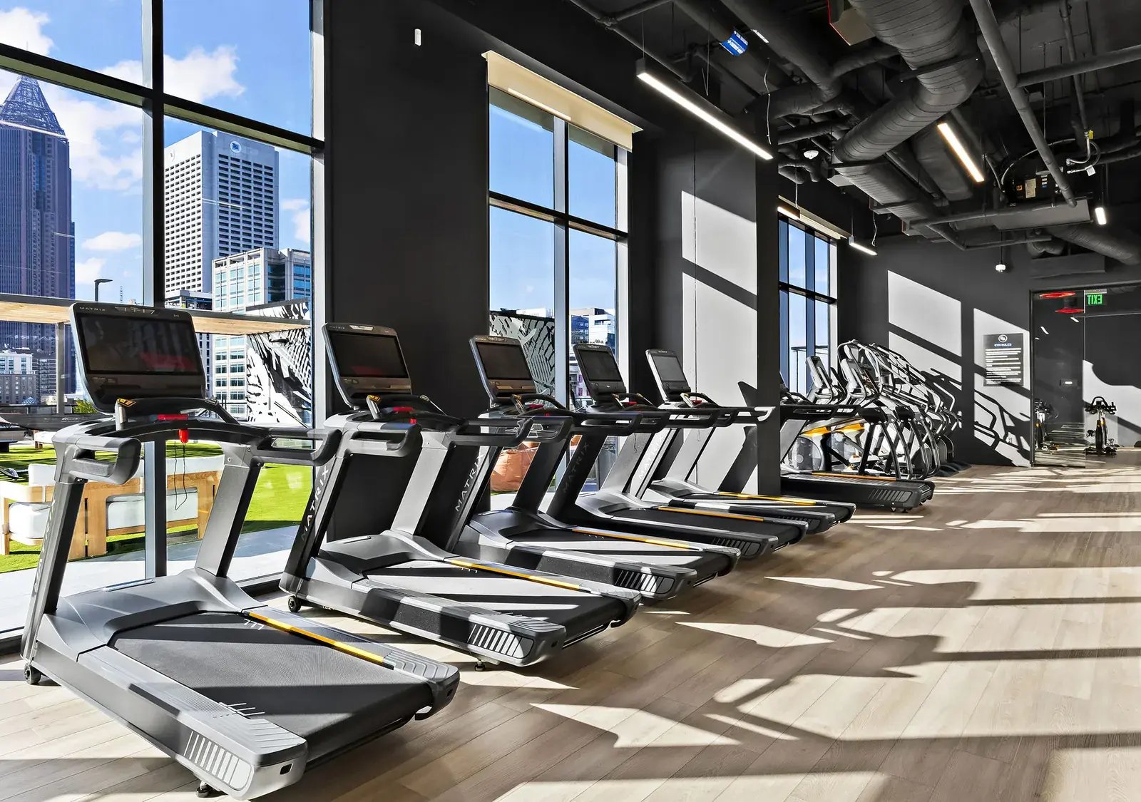 Row of Matrix treadmills facing floor-to-ceiling windows with a city skyline view